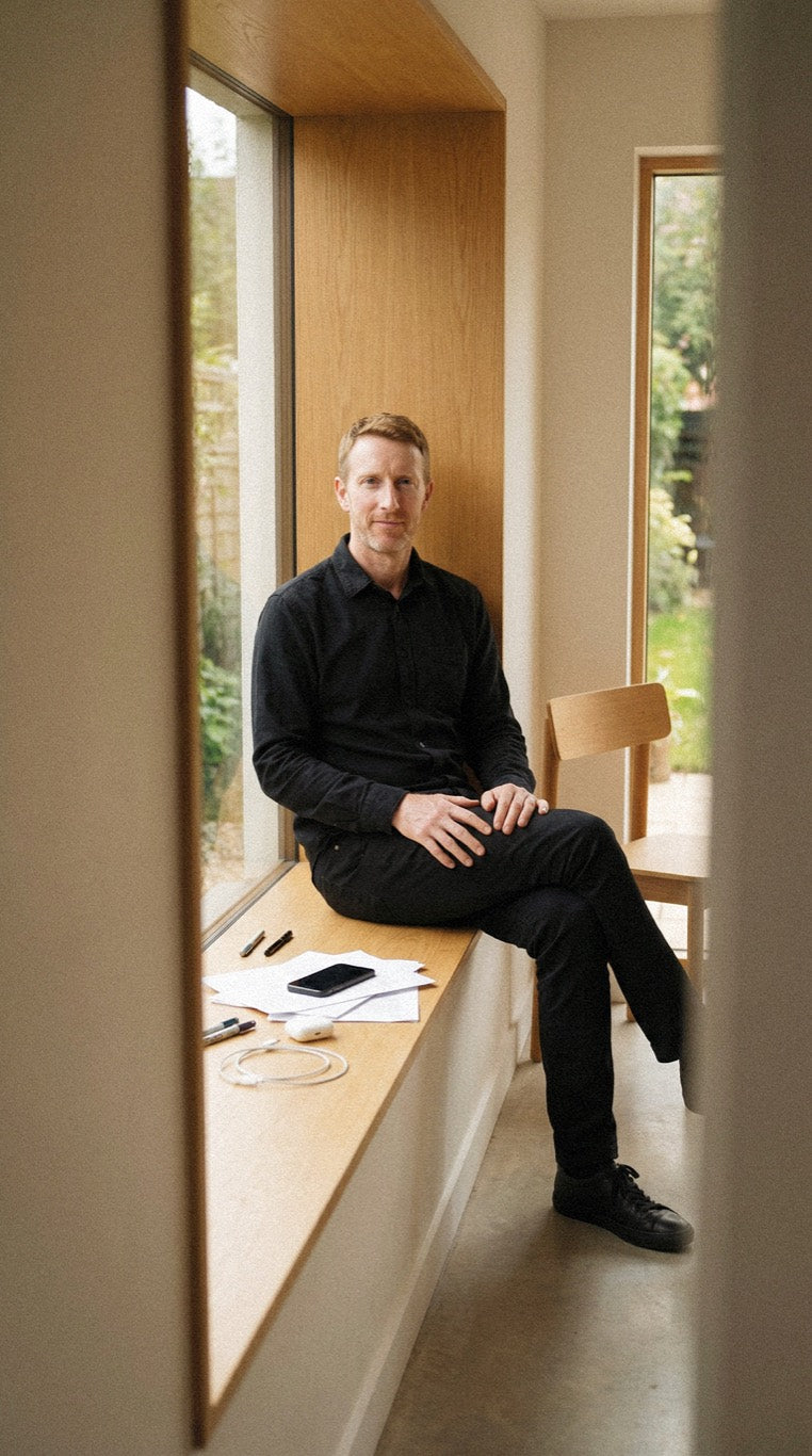 Man sitting on a window bench in a minimalist room, calm and self-assured