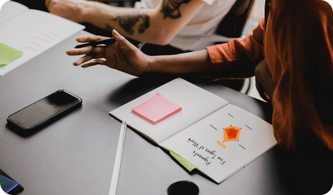 Woman in business attire surrounded by scattered papers and documents on a desk, illustrating work overwhelm and energy drain