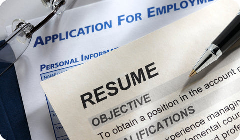 Close-up of a colorful graphic designer resume with colored skill bars in blue, orange, pink, and yellow, a profile photo, pie chart graphics, and a pen resting on top of a dark notebook.