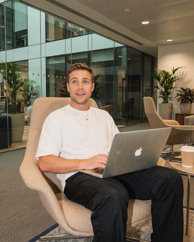 Person in a white shirt working on a laptop in a modern office chair.