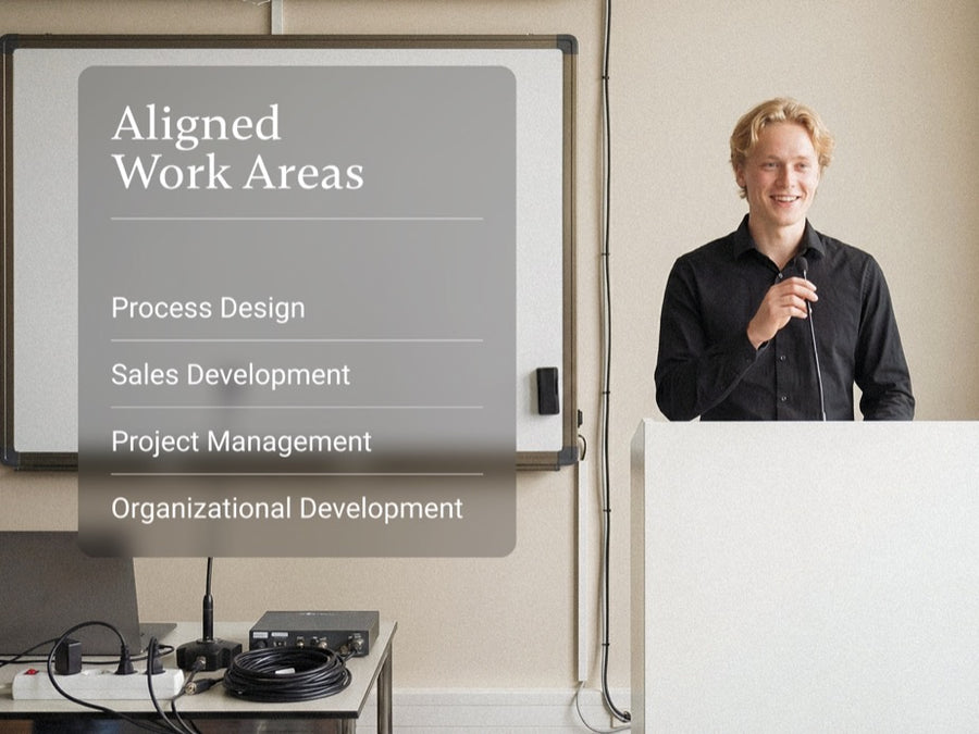 Student presenting next to whiteboard showing Pigment Aligned Work Areas including Process Design and Sales Development.