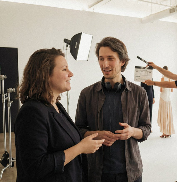 Two colleagues talking on a photo-studio set with lighting equipment